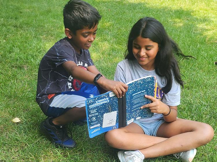 Two children reading a copybook